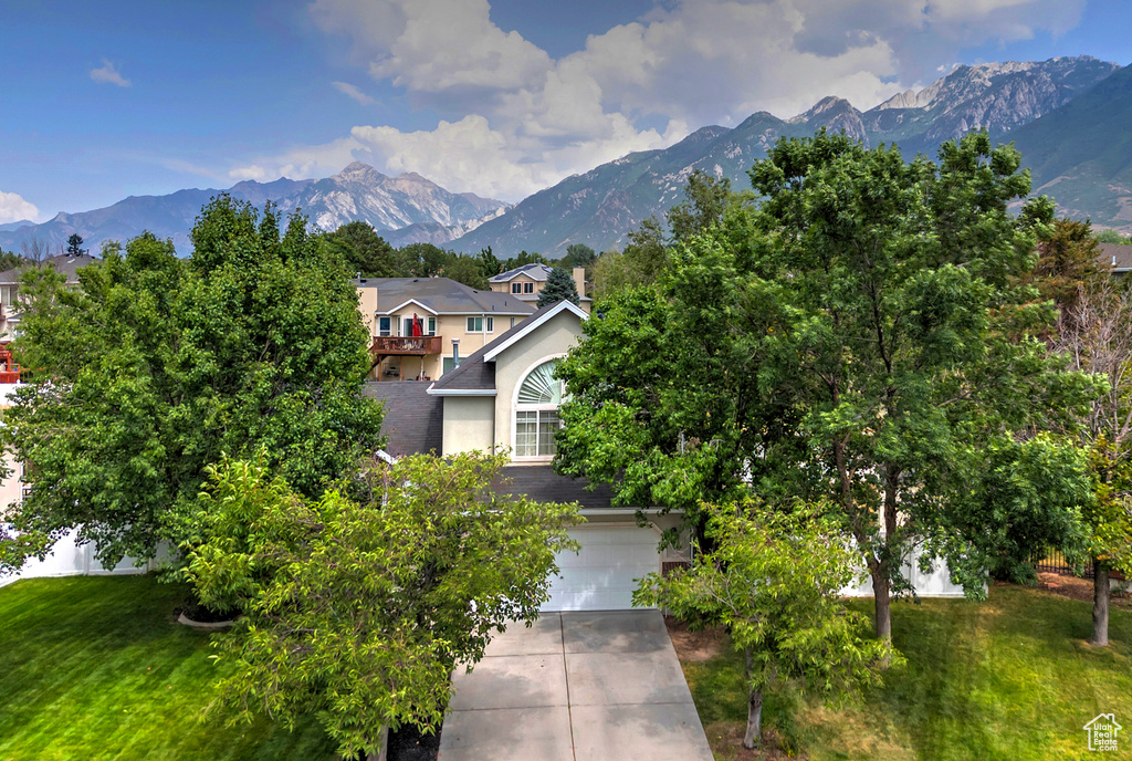 Obstructed view of property featuring stucco siding, a mountain view, and driveway