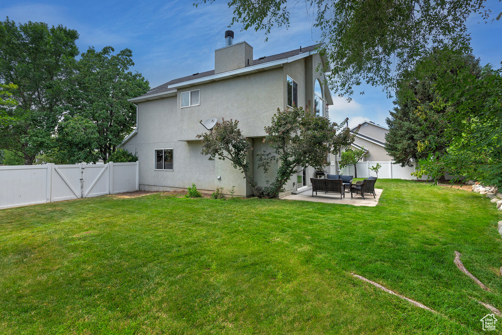 Back of property featuring a fenced backyard, a patio area, stucco siding, and a gate