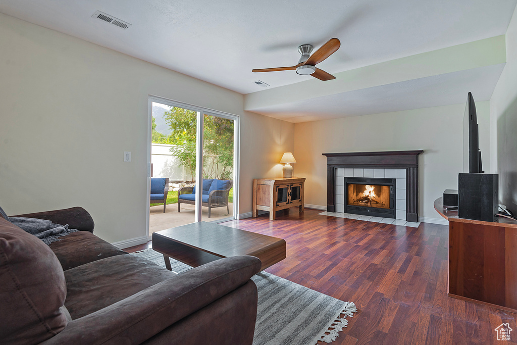 Living room with wood finished floors, a ceiling fan, and a fireplace
