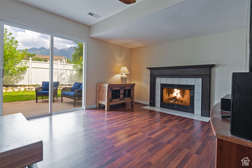 Living area featuring a mountain view, wood finished floors, a tile fireplace, and a ceiling fan
