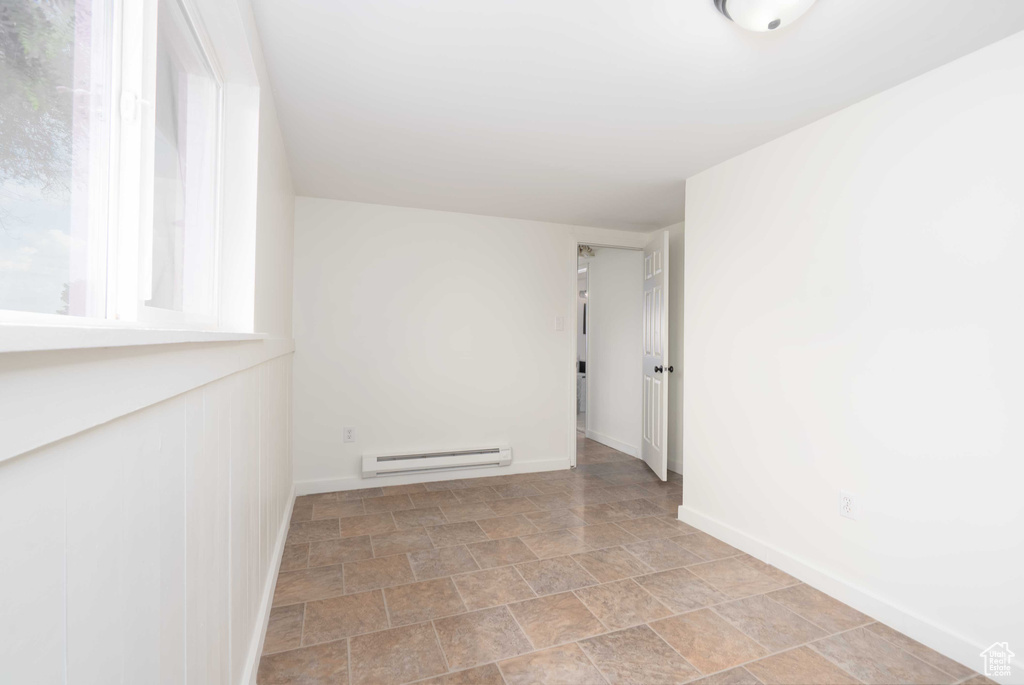 Spare room with a baseboard heating unit and stone finish floors