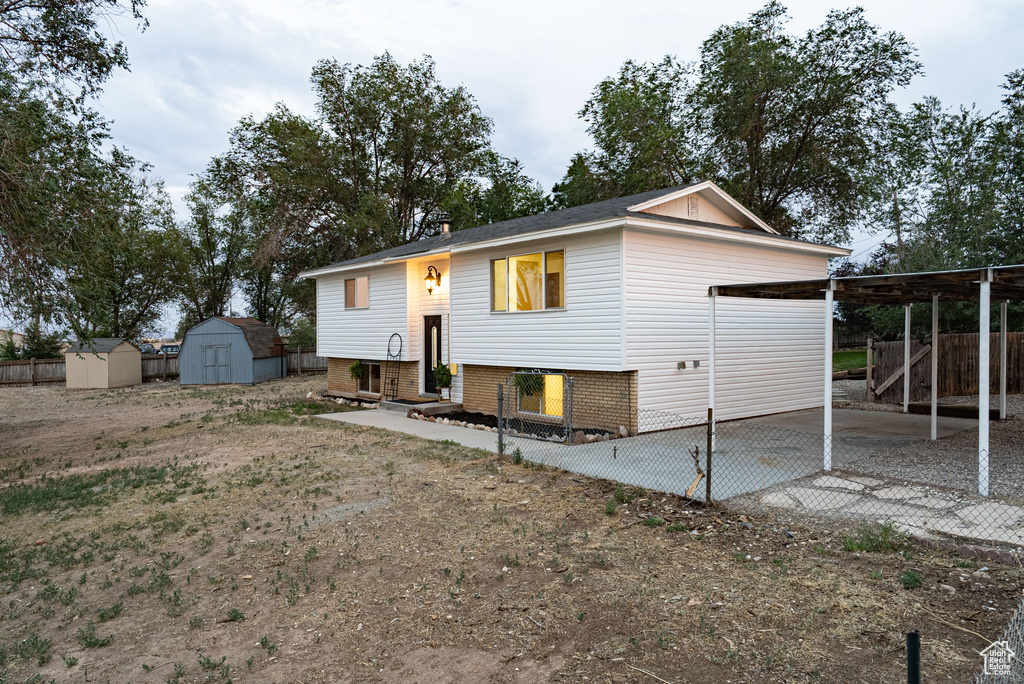 Rear view of house featuring a storage shed, driveway, a patio, and brick siding