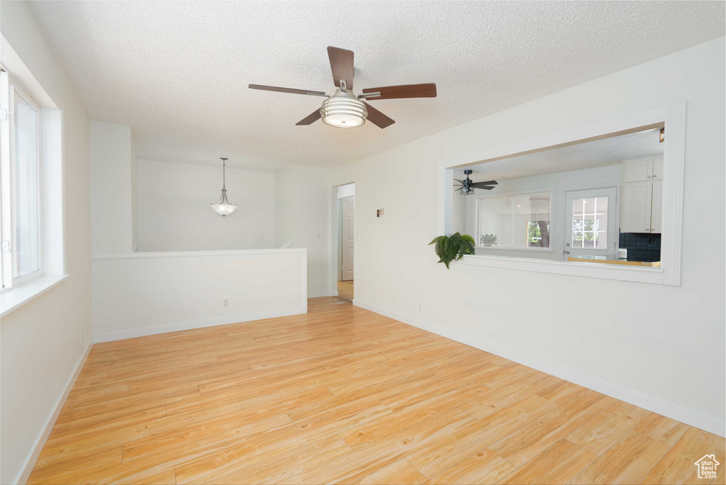 Spare room with light wood finished floors, a ceiling fan, and a textured ceiling