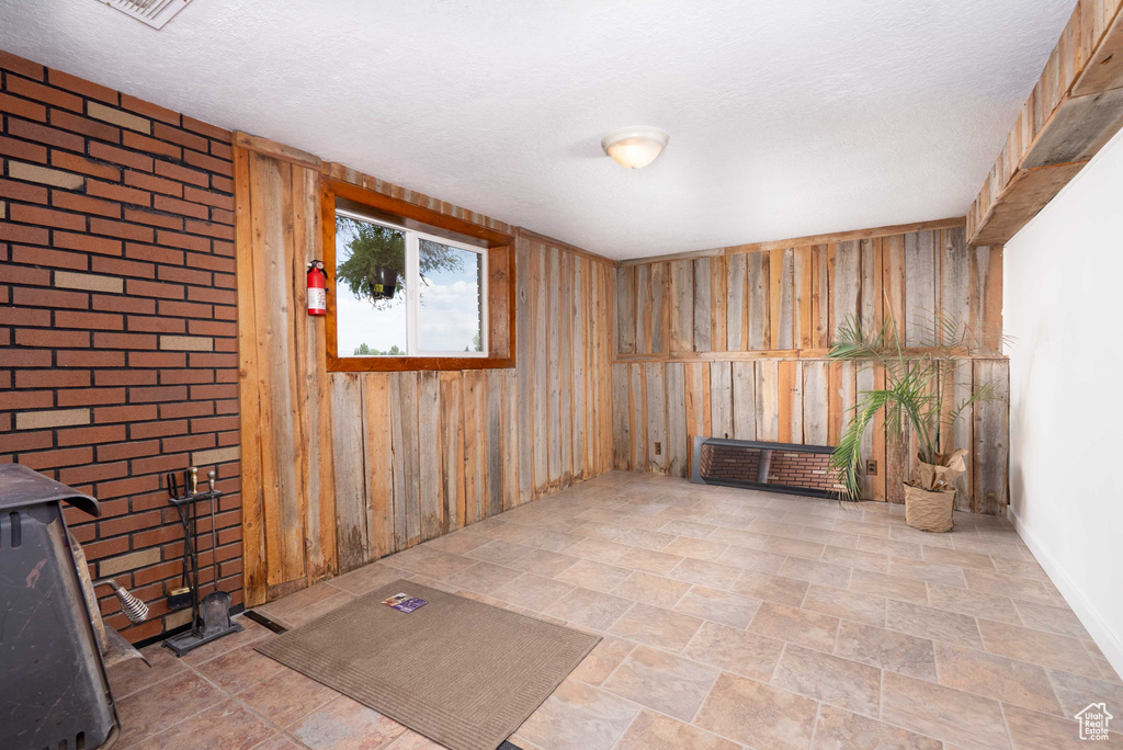 Empty room featuring wooden walls, a wood stove, and stone finish flooring