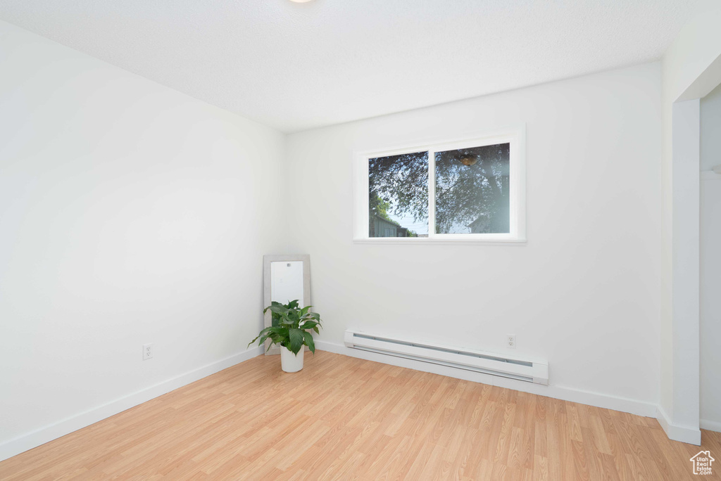 Unfurnished room with a baseboard radiator and wood finished floors