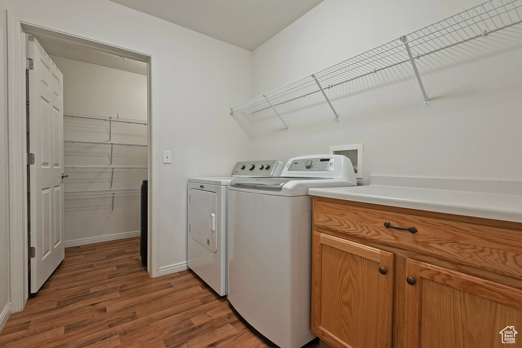 Laundry room with wood finished floors and washer and dryer