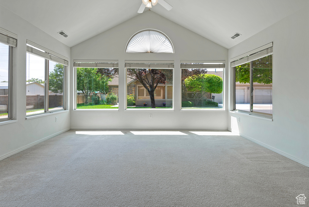 Unfurnished sunroom featuring healthy amount of natural light, carpet flooring, and vaulted ceiling