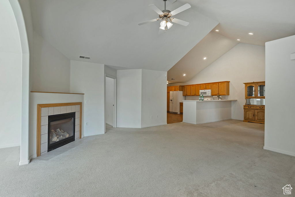 Unfurnished living room featuring light colored carpet, recessed lighting, a ceiling fan, a fireplace, and high vaulted ceiling