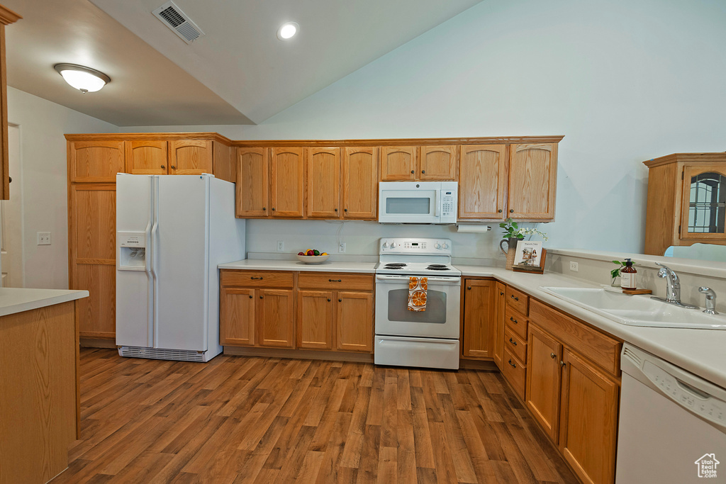 Kitchen featuring white appliances, light countertops, wood finished floors, and high vaulted ceiling