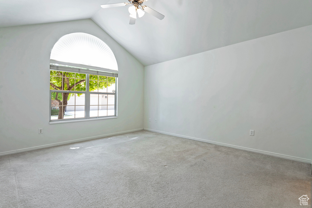 Carpeted spare room with vaulted ceiling and a ceiling fan