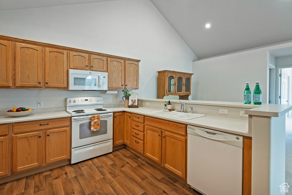 Kitchen featuring a peninsula, high vaulted ceiling, white appliances, light countertops, and dark wood-style floors