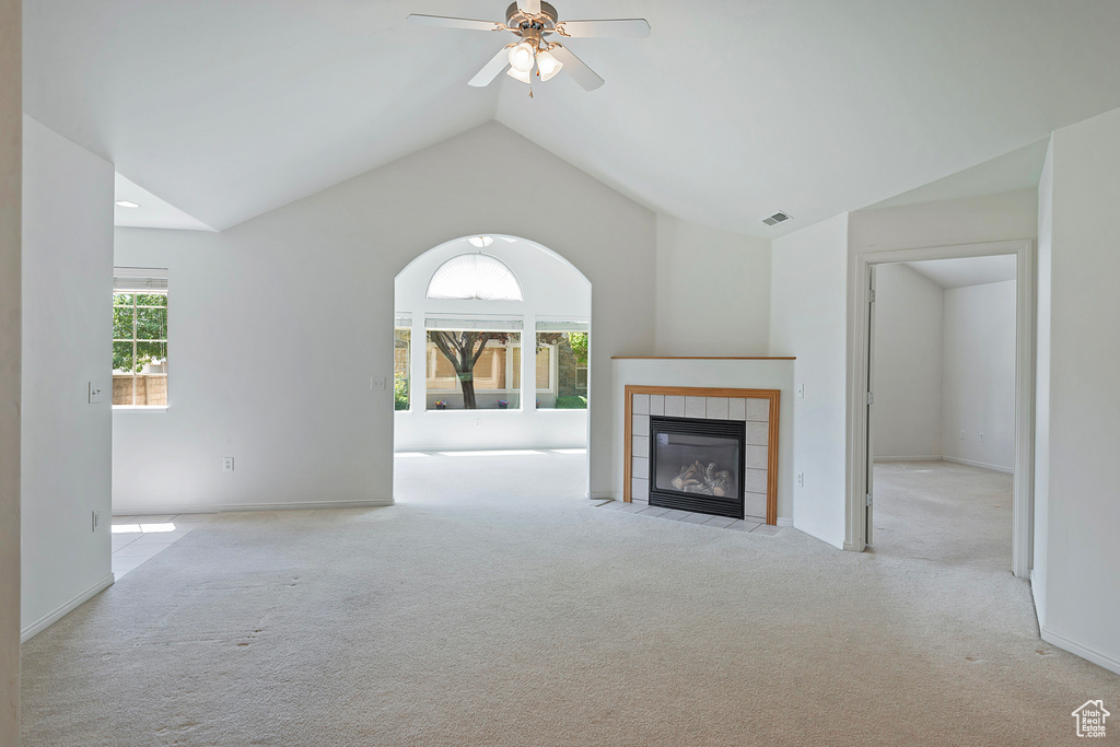 Unfurnished living room with carpet floors, a tile fireplace, a ceiling fan, and vaulted ceiling