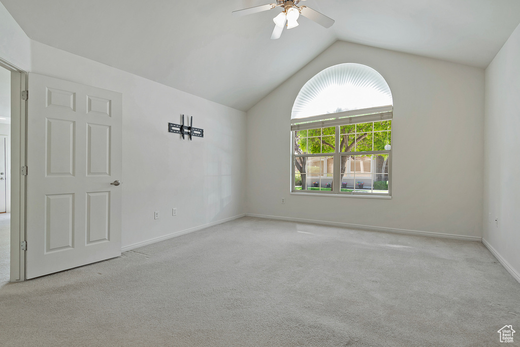 Empty room featuring carpet, lofted ceiling, and ceiling fan