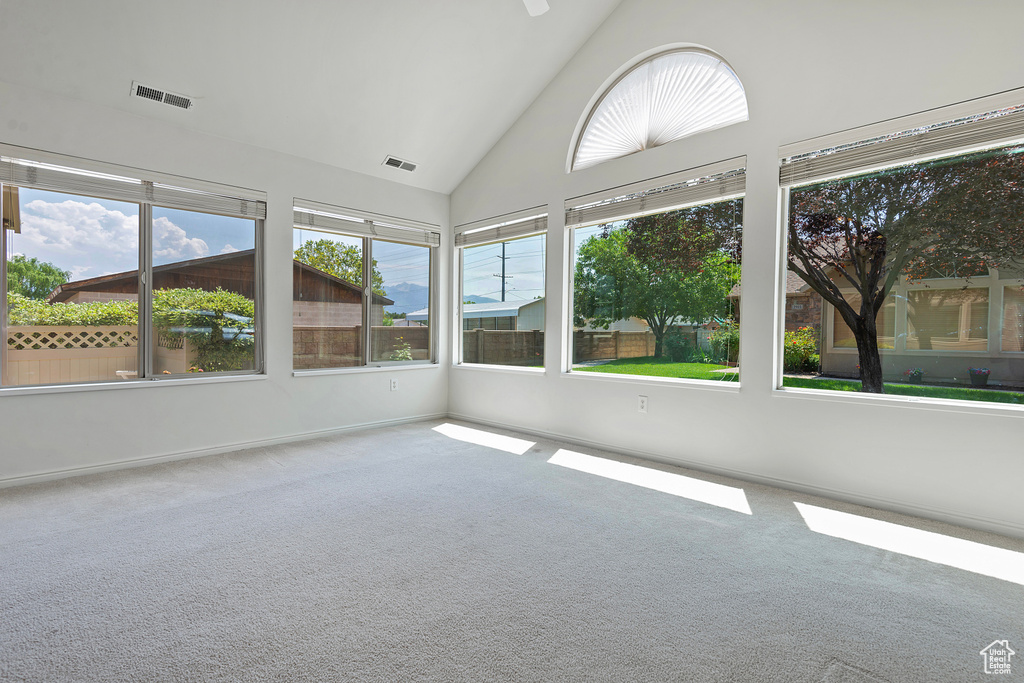 Unfurnished sunroom featuring carpet flooring and high vaulted ceiling