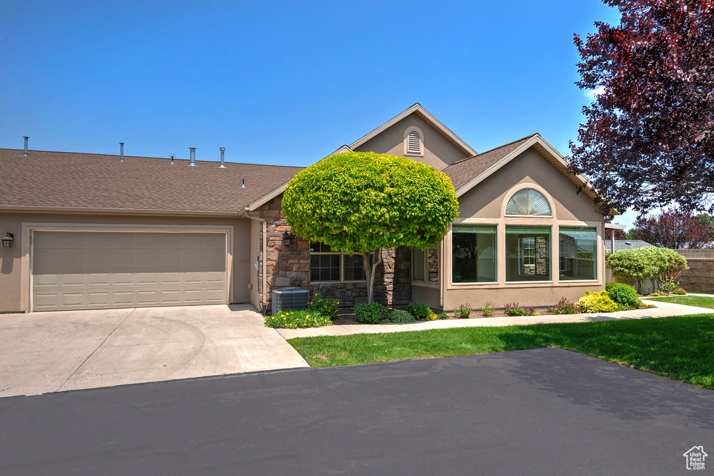View of front of house with an attached garage, stucco siding, roof with shingles, concrete driveway, and stone siding
