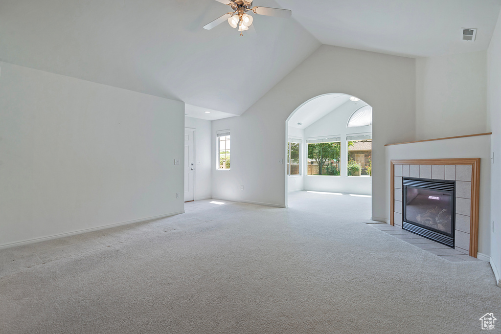 Unfurnished living room with ceiling fan, carpet, a tile fireplace, and high vaulted ceiling