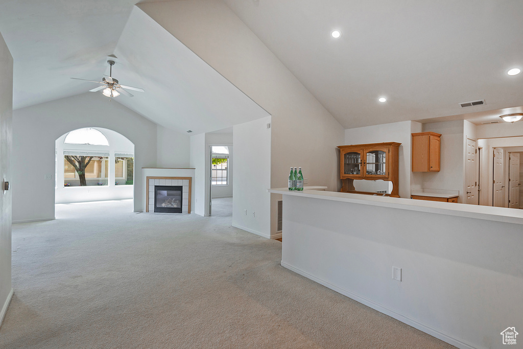 Unfurnished living room with vaulted ceiling, a ceiling fan, light carpet, recessed lighting, and a fireplace