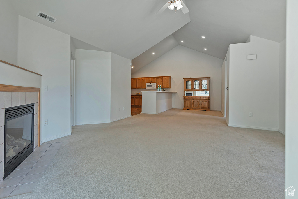 Unfurnished living room featuring high vaulted ceiling, light carpet, a fireplace, recessed lighting, and a ceiling fan