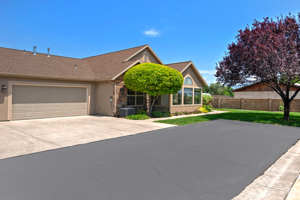 View of front facade with stucco siding, a garage, a shingled roof, concrete driveway, and stone siding