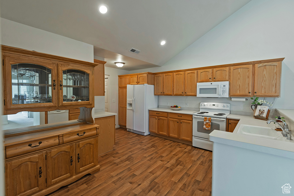Kitchen featuring white appliances, light countertops, wood finished floors, recessed lighting, and high vaulted ceiling