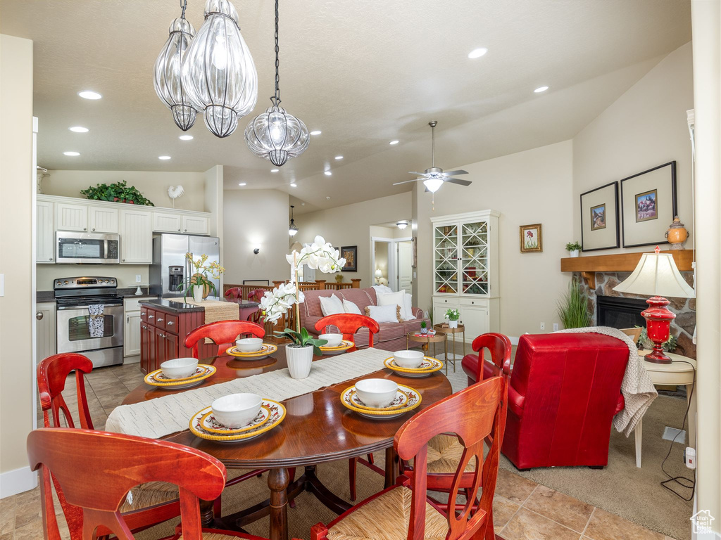 Dining room featuring lofted ceiling, a ceiling fan, recessed lighting, and a stone fireplace