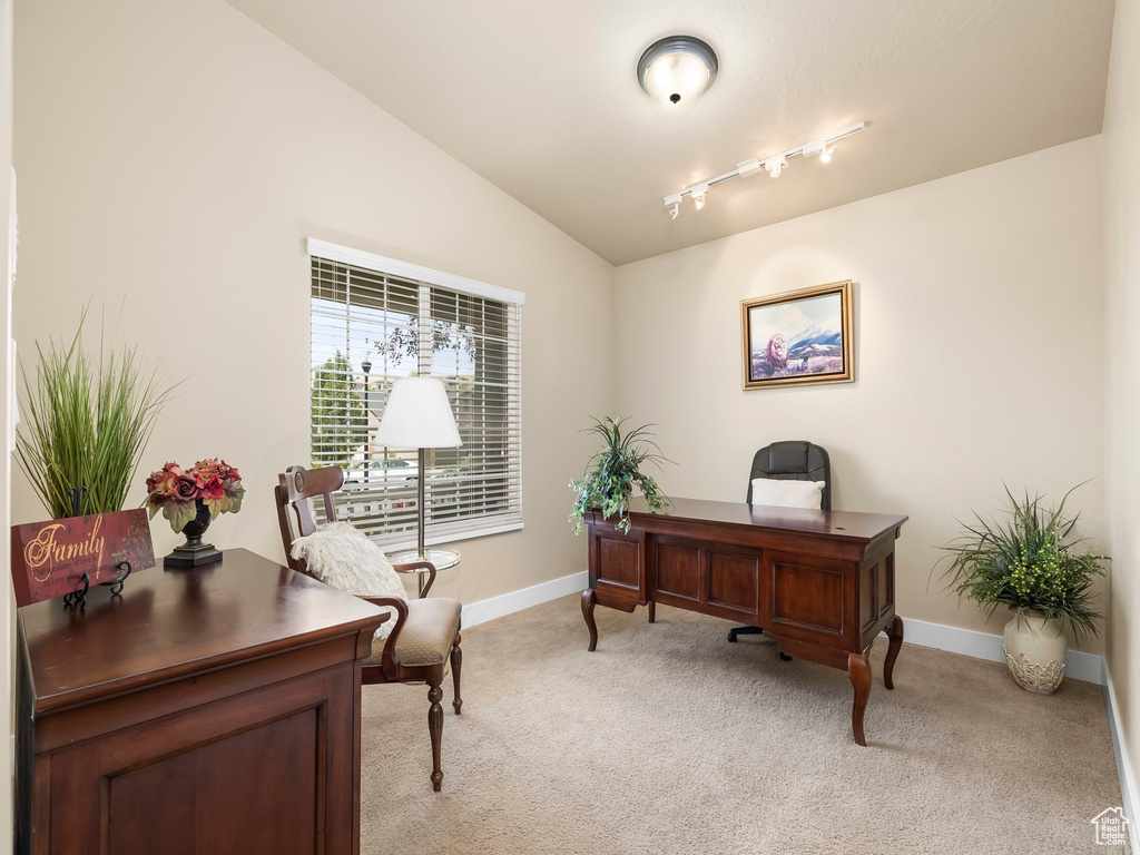 Home office with light carpet, vaulted ceiling, and track lighting