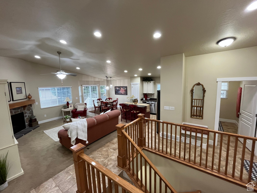 Living area with recessed lighting, a stone fireplace, light colored carpet, a ceiling fan, and lofted ceiling