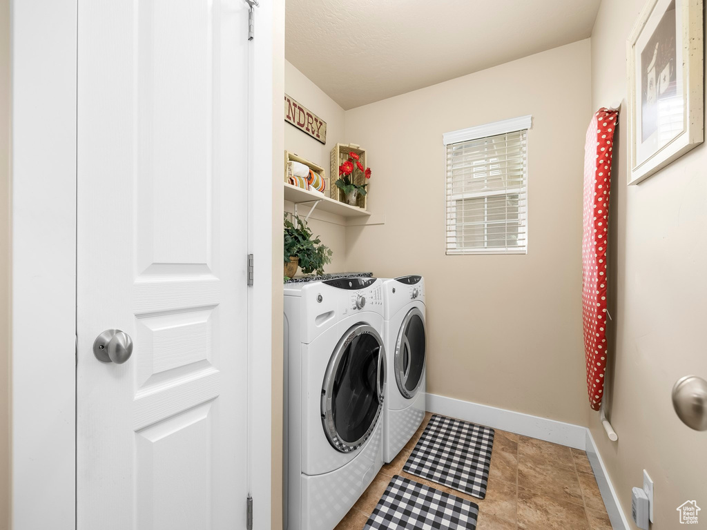 Washroom with washing machine and clothes dryer and baseboards