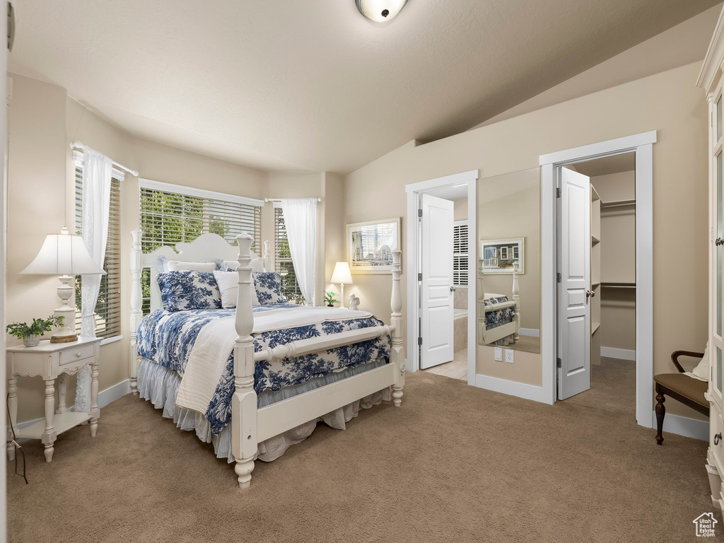 Bedroom featuring light carpet, lofted ceiling, a spacious closet, and ensuite bathroom