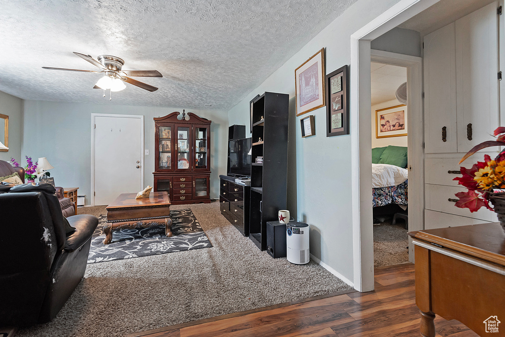 Living room featuring wood finished floors, ceiling fan, and a textured ceiling