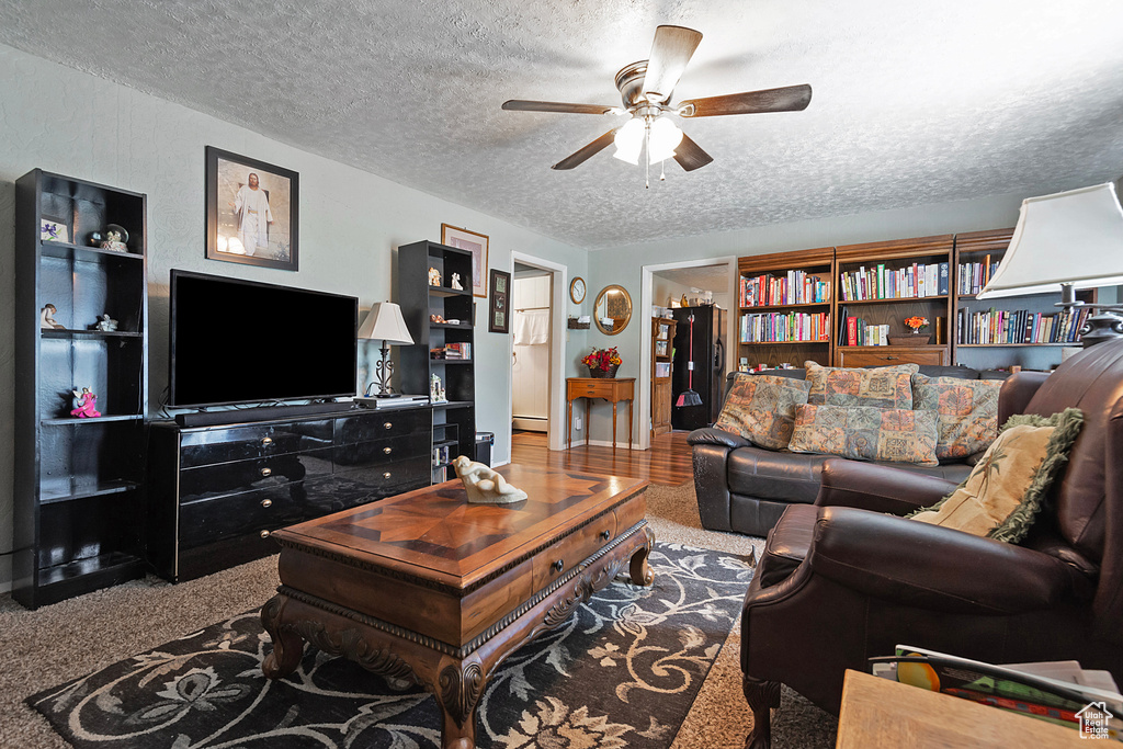 Carpeted living room featuring ceiling fan, a textured ceiling, and a baseboard radiator
