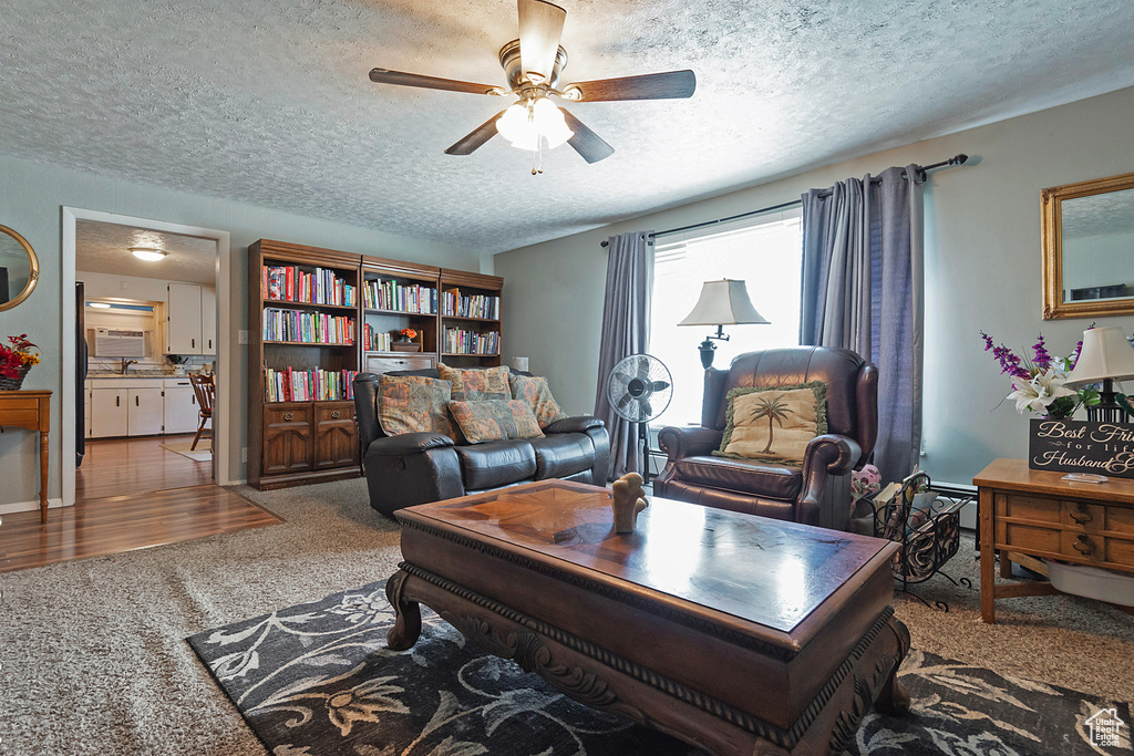 Carpeted living area with a textured ceiling and ceiling fan