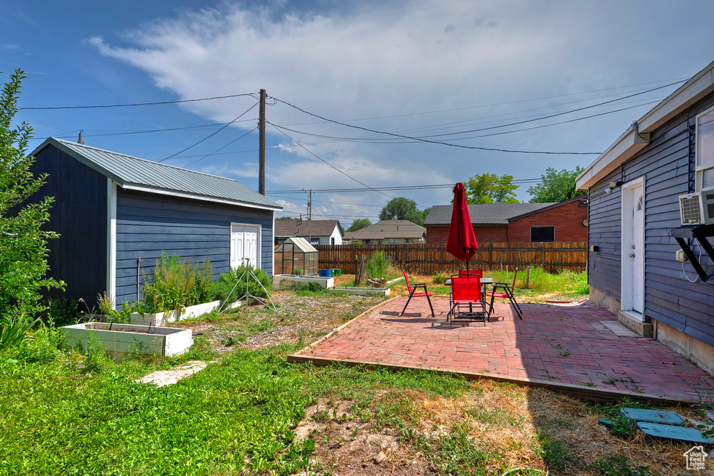 View of yard with a garden, an outdoor structure, and a patio