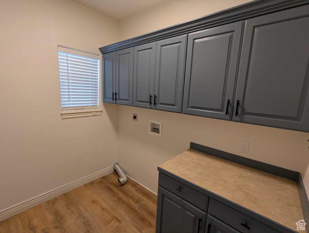 Laundry area featuring cabinet space, electric dryer hookup, washer hookup, and light wood-type flooring