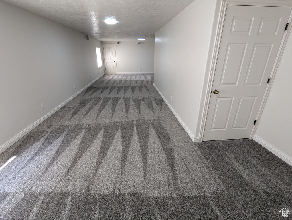 Hallway with carpet floors and a textured ceiling