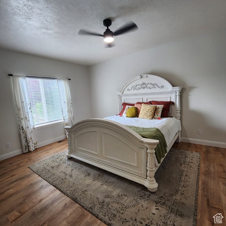 Bedroom with wood finished floors, ceiling fan, and a textured ceiling