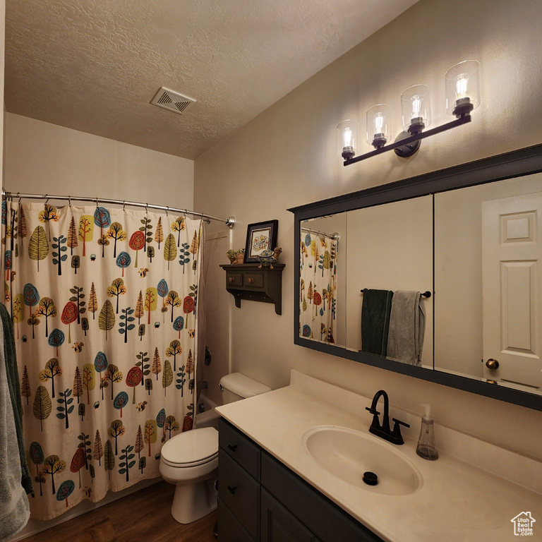 Bathroom featuring vanity, wood finished floors, a textured ceiling, and shower / bath combo with shower curtain