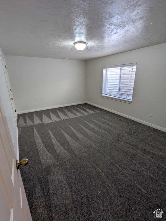 Unfurnished room featuring dark carpet and a textured ceiling