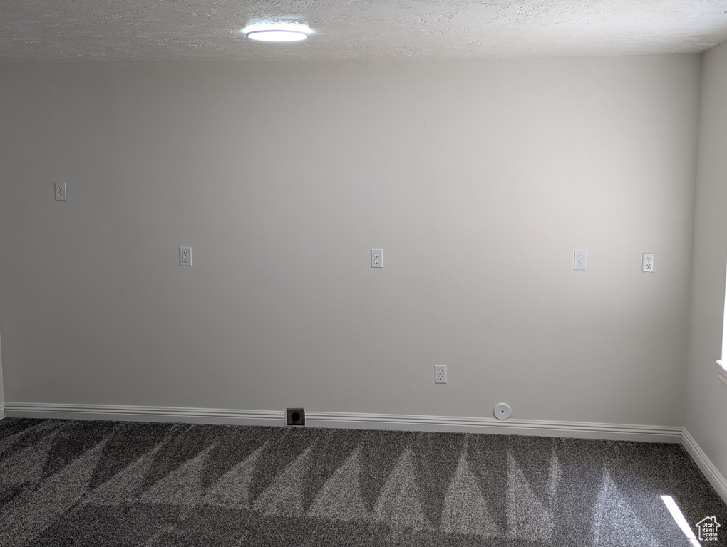 Carpeted spare room with a textured ceiling and baseboards