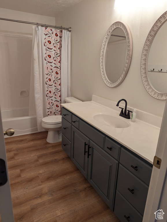 Full bathroom with vanity, wood finished floors, and shower / tub combo with curtain