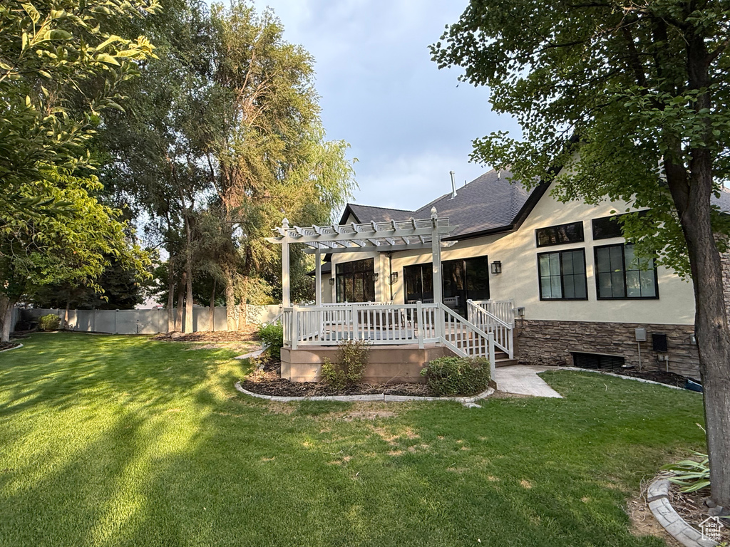 Back of house with stone siding, a pergola, a wooden deck, and a shingled roof