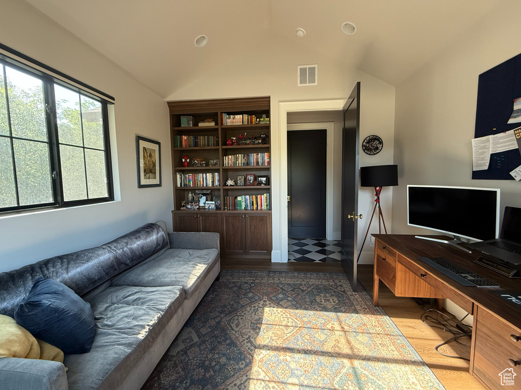 Living area with vaulted ceiling, wood finished floors, and an office area