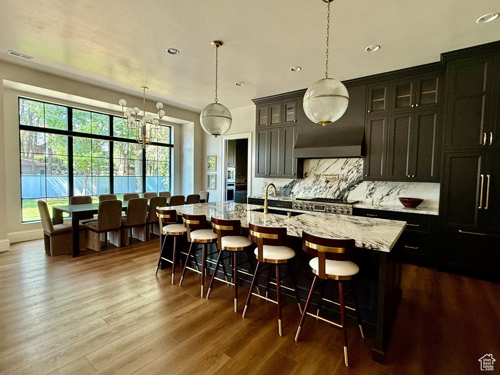Kitchen with healthy amount of natural light, decorative backsplash, recessed lighting, a center island with sink, and dark wood finished floors