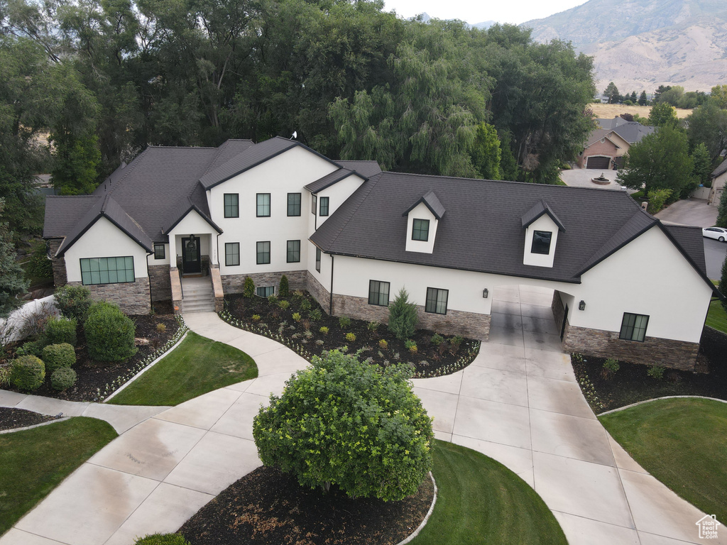 Modern inspired farmhouse with stucco siding, stone siding, concrete driveway, and a garage