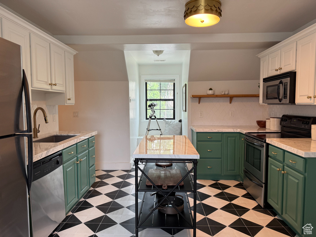 Kitchen featuring green cabinets, appliances with stainless steel finishes, white cabinetry, and light countertops
