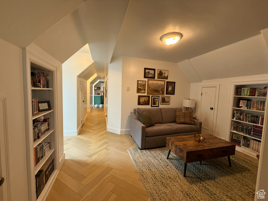 Living area featuring built in shelves and vaulted ceiling