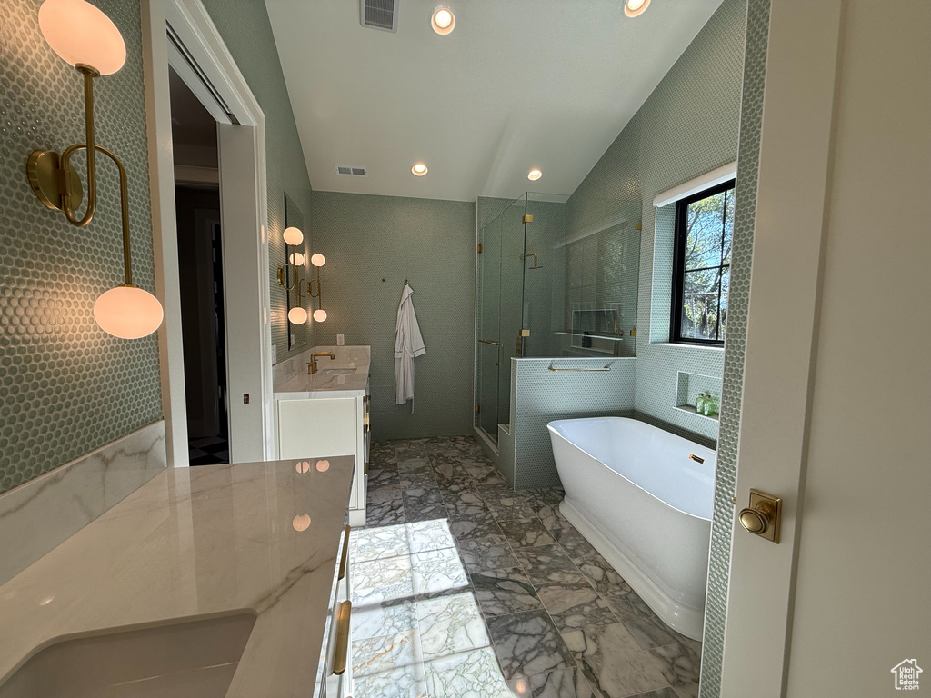 Bathroom featuring marble tiled flooring, a stall shower, vanity, a freestanding bath, and recessed lighting