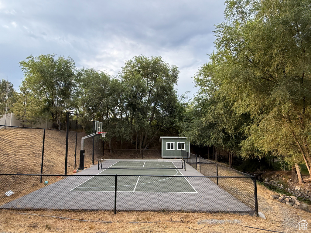 View of basketball court with a tennis court, community basketball court, and view of scattered trees
