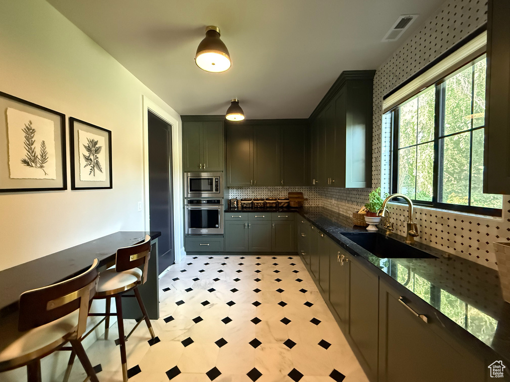Kitchen featuring dark countertops, appliances with stainless steel finishes, decorative backsplash, and light floors