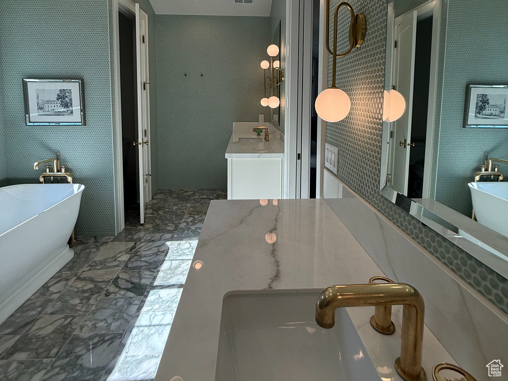 Bathroom featuring a freestanding tub, marble finish flooring, vanity, and recessed lighting